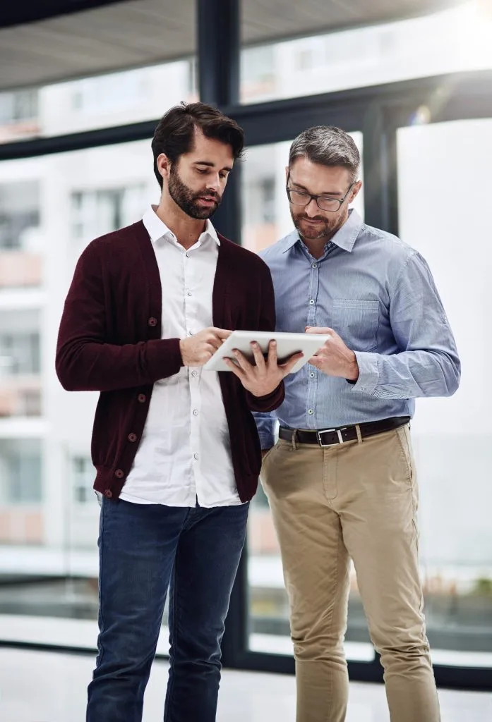 Employee showing work to his colleague on his tablet at the office
