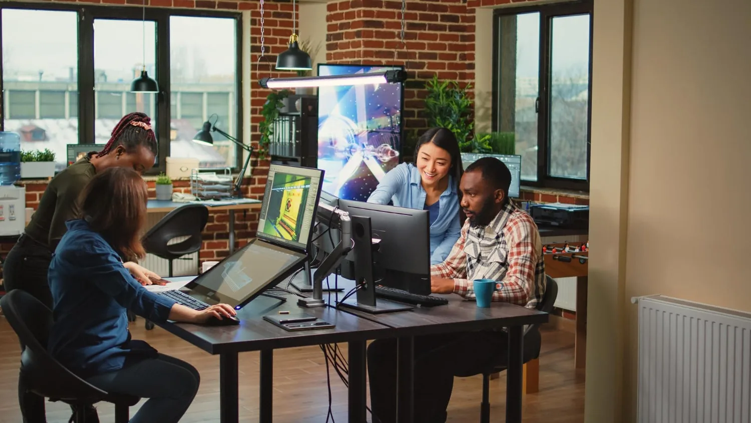 A team of IT professionals collaborating in a modern office with multiple screens displaying digital projects. One colleague assists another, reflecting the benefits of IT staffing solutions.